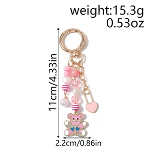 Détail d'un porte-clés ours rose avec perles, breloques en cœur doré et perles nacrées