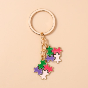 Détail de porte-clés cœur puzzle en métal doré avec incrustations en émail coloré