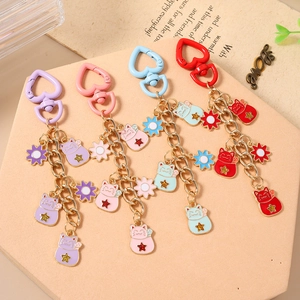 Cartoon Maneki Neko keychain featuring heart-shaped hooks and floral star enamel charms