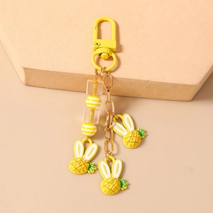 Dettaglio di ciondoli a forma di coniglio ananas giallo con gancio opaco e catena