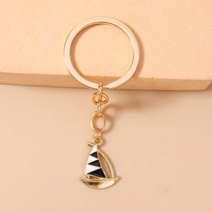 Close-up of golden alloy sailboat keychain with black and white enamel detail