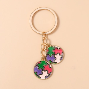 Détail d'un porte-clés puzzle cœur doré avec pendentifs en émail coloré sur fond beige