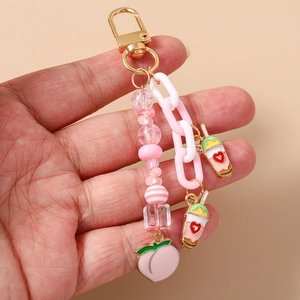 Détail des breloques pêche et thé aux perles sur un porte-clés à chaîne rose