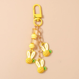Dettaglio di un portachiavi creativo con coniglio ananas, ciondolo in resina gialla e catena