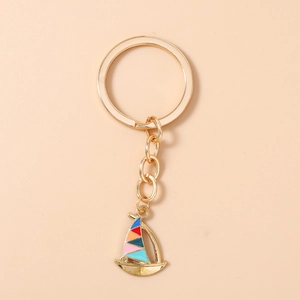 Close-up of golden sailboat keychain with vibrant multicolor enamel sails and metal ring