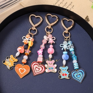 Colorful beaded teddy bear and heart keychains with gold heart clips in a tray