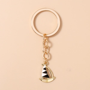 Detailed macro of a gold-plated sailing boat keychain with nautical black and white sail