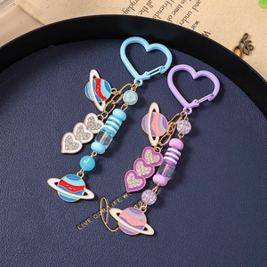 Porte-clés avec perles, cœurs et planètes dans les tons bleu et violet sur un plateau