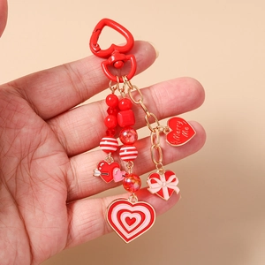 Detail of red heart keychain featuring beaded charms and Merry Me engraved pendant