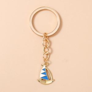 Detailed top view of a gold sailboat keychain with blue and white enamel inlay