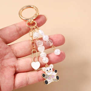 Gros plan détaillé d'un porte-clés à la mode avec perles, breloque coeur et ours mignon