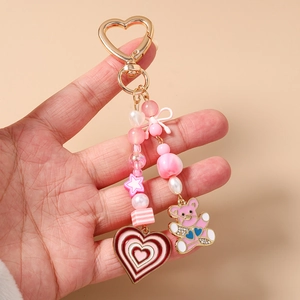 Detailed macro of pink beaded keychain with heart clasp and cute bear charm for bags