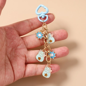 Close-up of light blue lucky cat charms and flower pendants on a heart-shaped keychain