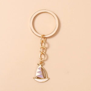 Detailed close-up of a gold sailboat keychain with purple and white enamel finish