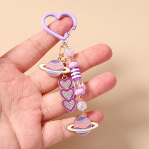Détail d'un porte-clés à perles mauves avec breloques planètes et coeurs en cristal