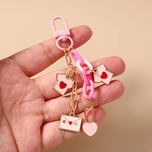 Detail of pink enamel heart and letter envelope charms on a chunky gold link chain