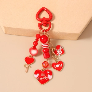 Detail of red heart-shaped keychain with beaded charms and Be Lovely engraved pendants