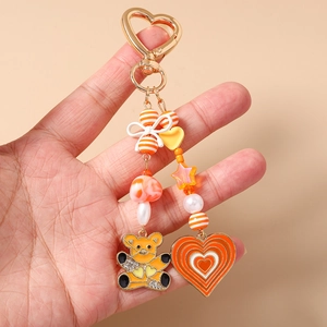 Detailed shot of beaded bear keychain with orange heart charms and ribbon bow decor