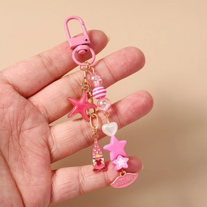 Pink keychain detail with star charms, gnome pendant and KISS ME lip tag on gold chain