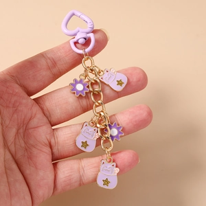 Detail of purple cartoon lucky cat keychain with heart clip held in hand