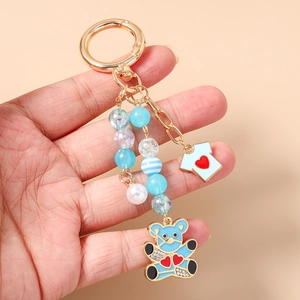 Détail d'un porte-clés ourson bleu avec charms en émail et perles colorées en gros plan