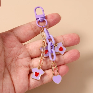 Detail of purple chain keychain featuring cute t-shirt charms and gold accents held by hand