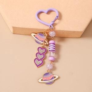 Détail du porte-clés cœur violet avec pendentifs planète dorés et ornements perles