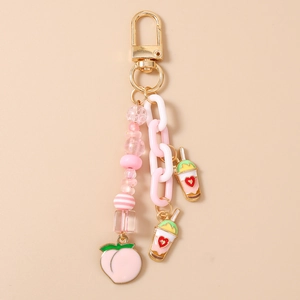Gros plan de charms thé au lait rose et pendentifs cœur sur un porte-clés doré