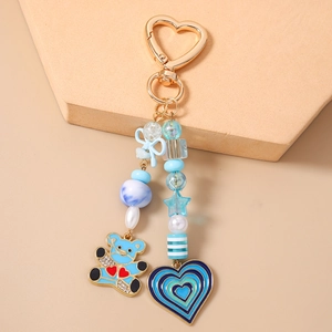 Detail of beaded keychain with blue bear charm and gold heart clasp on display stand