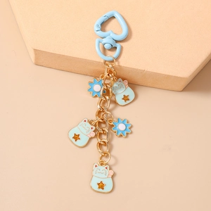 Close-up of blue lucky cat and sunflower charms on a golden chain with heart clasp