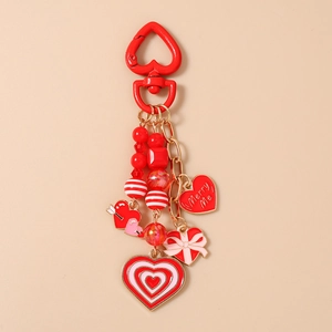Detail of red heart keychain with beads, gold chain and Merry Me charm pendant