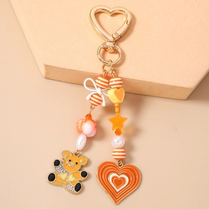 Detail of beaded keychain with golden heart clasp, striped beads and orange crystal bear