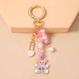 Détail d'un porte-clés ours rose avec anneau doré et perles nacrées roses