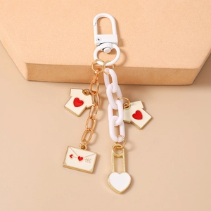 Detail view of heart chain keychain with enamel shirt and envelope charms on stone stand