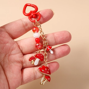 Détail d'un porte-clés champignon perlé avec fermoir cœur rouge et breloques en émail