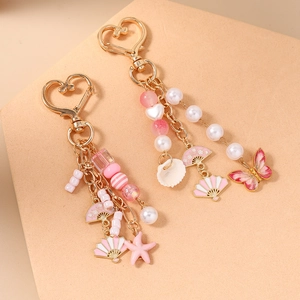 Pink beaded keychain with gold heart clasp featuring butterfly, fan and starfish charms