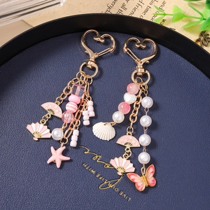 Chic gold starfish and shell beaded keychain with butterfly charms and pink accents