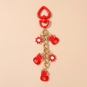 Detail of red and gold Maneki-neko keychain charms with heart clasp and floral pendants