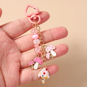 Gros plan d'un porte-clés à fermoir cœur rose avec perles et breloques champignons