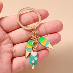 Détail d'un porte-clés avec breloques crème glacée et popsicle bleu tenu à la main