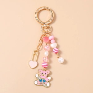 Vue détaillée du porte-clés ours rose avec breloques cœur dorées et perles variées
