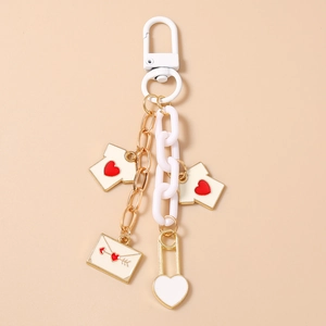Detail of heart keychain featuring white T-shirt charms and gold chain with envelope pendant