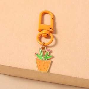 Detailansicht eines Kaktus-Schlüsselanhängers mit orangem Karabiner und Emaille-Blumenanhänger