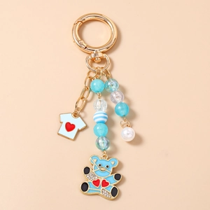 Détail d'un porte-clés à perles bleues avec pendentif ours, mini t-shirt et perle blanche