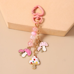 Détail d'un fermoir en forme de cœur rose et pendentifs champignons sur porte-clés perlé