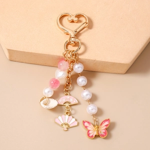 Detail of pink butterfly and fan keychain with gold heart clasp and pearls