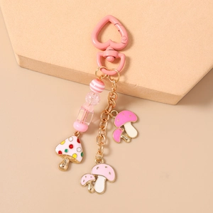 Détail du porte-clés champignon rose perlé avec fermoir coeur sur support beige
