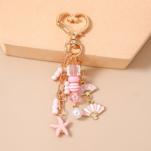 Pink starfish and fan enamel charms on a beaded keychain with a heart-shaped clasp