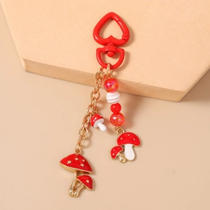 Détail de breloques champignons rouges avec fermoir coeur doré et perles sur le porte-clés
