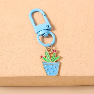 Detailaufnahme eines blauen Emaille-Kaktus-Schlüsselanhängers mit kleiner rosa Blume